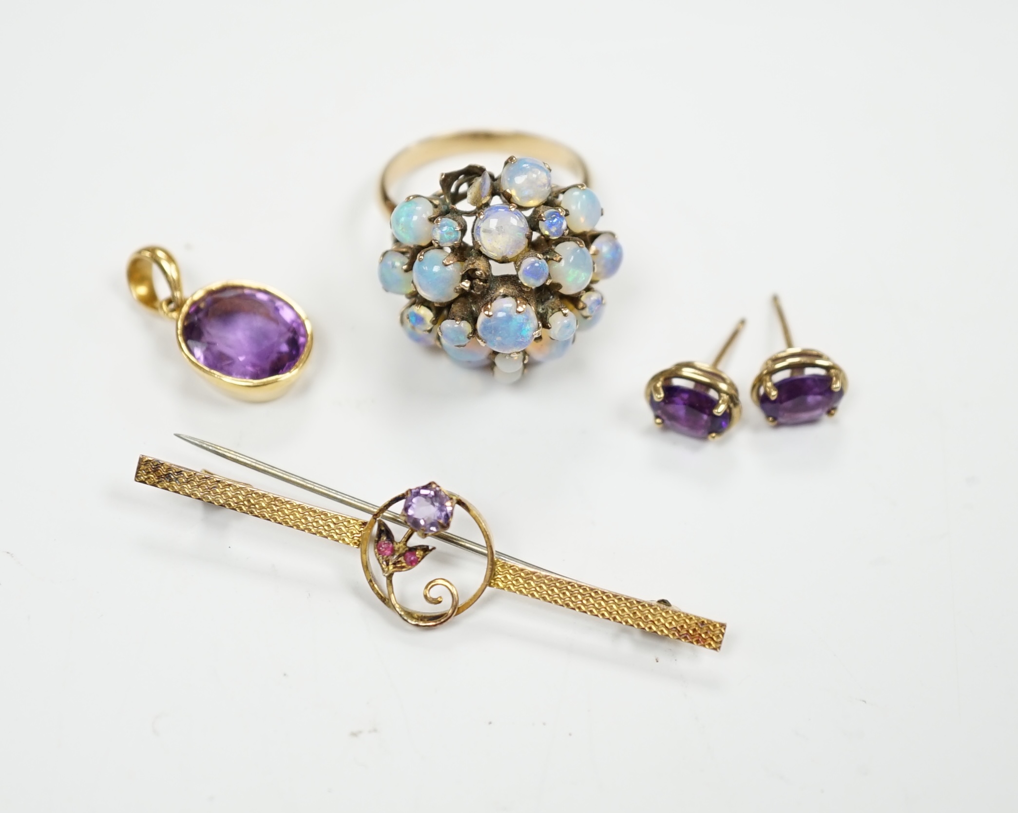 A cased 9ct, three stone amethyst and ruby set bar brooch, 49mm, a 14k and opal cluster set dress ring, a yellow metal and amethyst set pendant and a pair of similar ear studs.